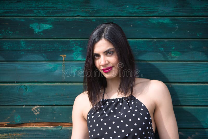 Retrato de una joven hermosa mujer con un vestido negro con puntos de polka blanco mirando a la cámara independiente y fortalecida fotografía de archivo