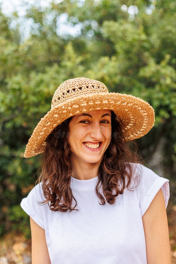 Retrato de una joven morena feliz con un sombrero de paja. la chica sonríe y disfruta sus vacaciones al aire libre foto de archivo