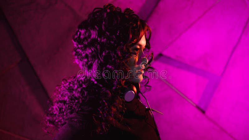 Retrato de una joven mujer sensual curridiza en grandes audífonos, sacada de la cabeza, y sombras, sobre fondo de neón foto de archivo libre de regalías