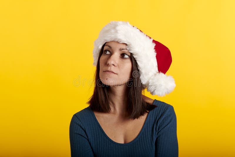 Retrato de una morena en un sombrero de santa claus con fondo amarillo fotografía de archivo libre de regalías