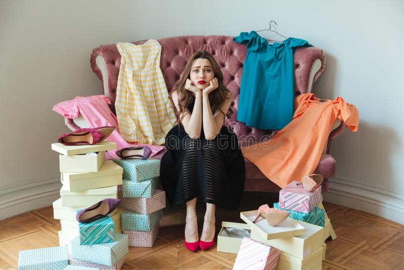 Retrato de una muchacha agotada cansada en el vestido que se sienta en un sofá fotos de archivo libres de regalías Retrato de una muchacha agotada cansada en el vestido que se sienta en un sofá fotos de archivo libres de regalías