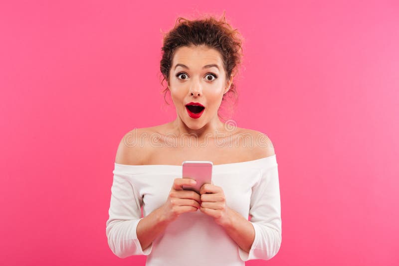 Retrato de una muchacha emocionada feliz que sostiene el teléfono móvil foto de archivo