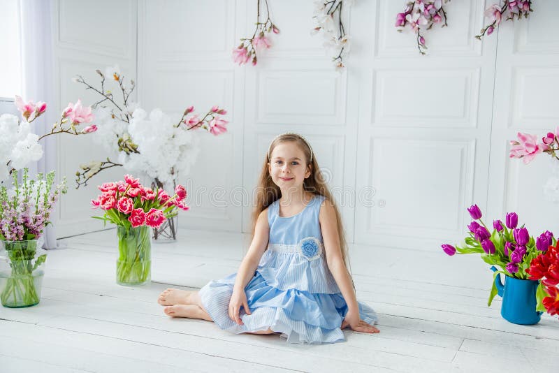 Retrato de una muchacha de ojos azules hermosa, niña entre las flores de la primavera en un cuarto brillante fotos de archivo libres de regalías Retrato de una muchacha de ojos azules hermosa, niña entre las flores de la primavera en un cuarto brillante fotos de archivo libres de regalías