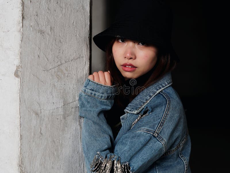 Retrato de una mujer china hermosa en los tejanos y el sombrero negro que miran derecho la cámara, muchacha linda con los ojos br fotografía de archivo Retrato de una mujer china hermosa en los tejanos y el sombrero negro que miran derecho la cámara, muchacha linda con los ojos br fotografía de archivo