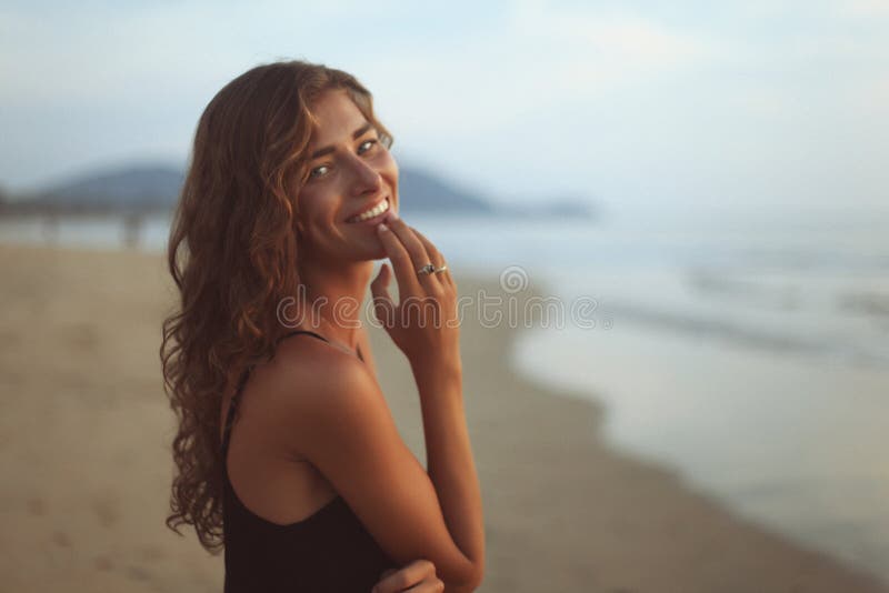 Retrato de una mujer hermosa joven con el pelo rizado largo en la playa fotografía de archivo Retrato de una mujer hermosa joven con el pelo rizado largo en la playa fotografía de archivo