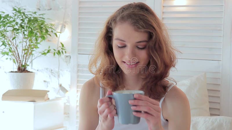 Retrato de una mujer joven feliz, ella bebe el café por la mañana