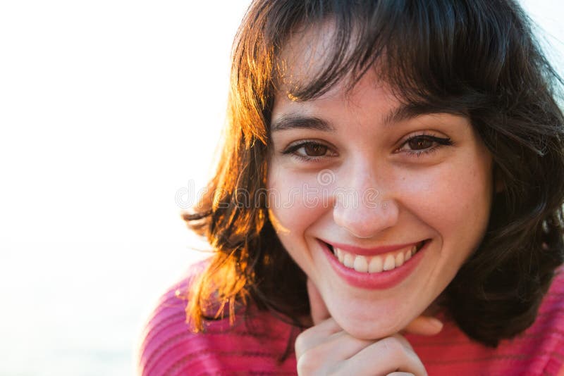 Retrato de una mujer joven sonriente en la puesta del sol foto de archivo Retrato de una mujer joven sonriente en la puesta del sol foto de archivo