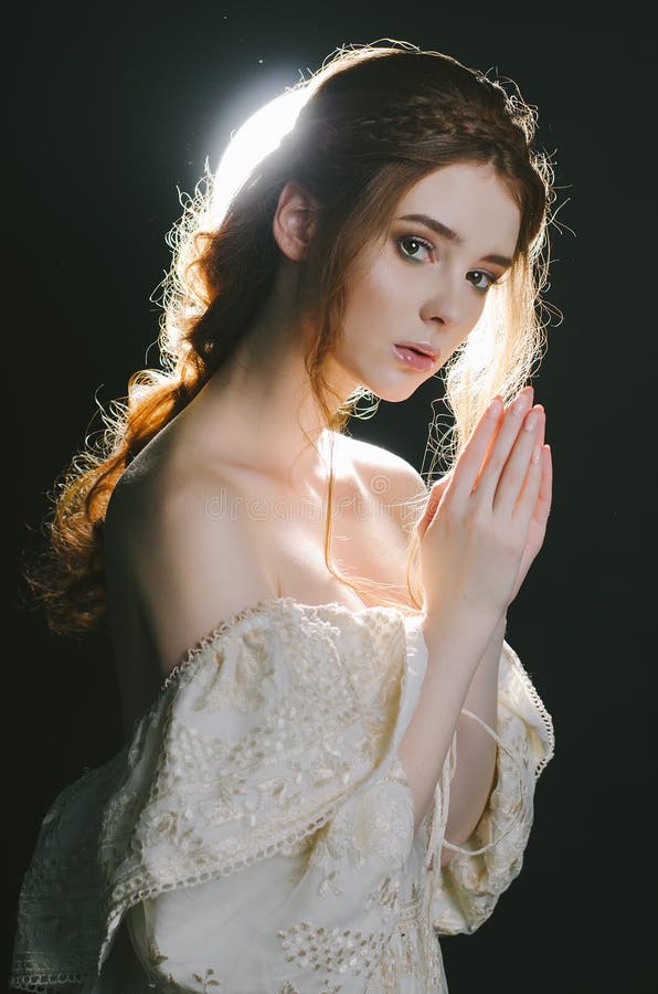 Retrato de una mujer pelirroja joven de rogación en vestido de la ceniza del vintage con los hombros abiertos en un fondo negro e imagenes de archivo Retrato de una mujer pelirroja joven de rogación en vestido de la ceniza del vintage con los hombros abiertos en un fondo negro e imagenes de archivo