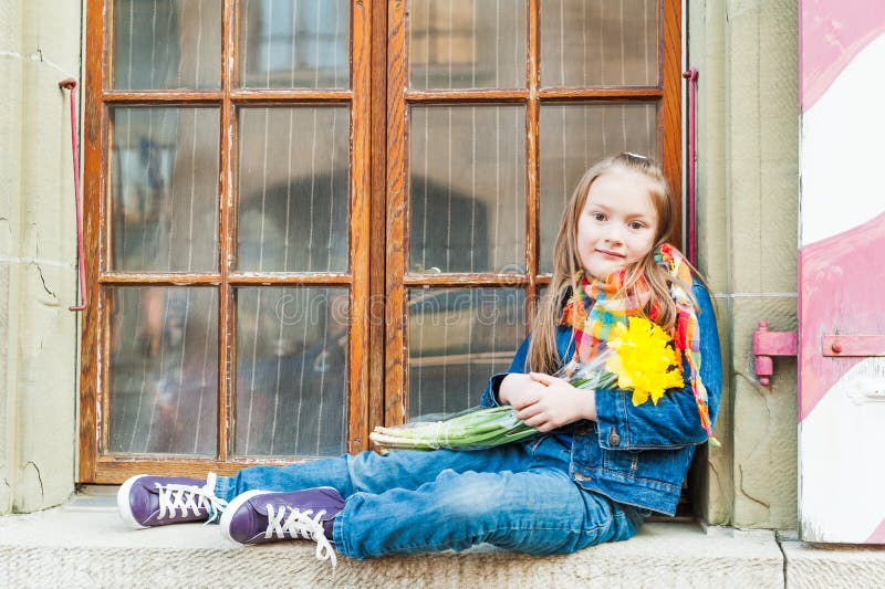 Outdoor portrait of a cute little girl with spring flowers narcisses, wearing, jeans clothes. Outdoor portrait of a cute little girl with spring flowers narcisses, wearing, jeans clothes