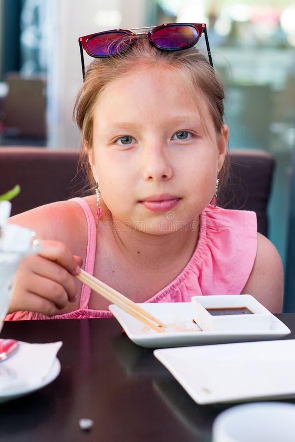 Retrato de una niña que come el sushi en restaurante asiático fotografía de archivo Retrato de una niña que come el sushi en restaurante asiático fotografía de archivo