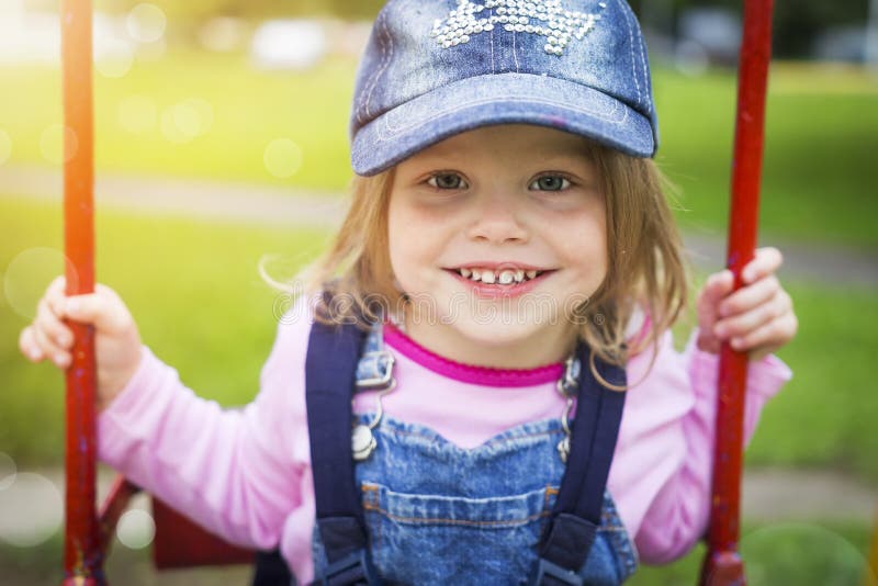 Retrato de una niña sonriente hermosa en un parque del verano en un oscilación Un bebé lindo feliz está montando en un oscilación imágenes de archivo libres de regalías Retrato de una niña sonriente hermosa en un parque del verano en un oscilación Un bebé lindo feliz está montando en un oscilación imágenes de archivo libres de regalías
