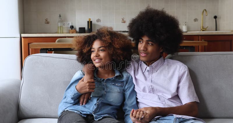 Retrato de una pareja de jóvenes africanos casados abrazándose en el sofá en casa almacen de metraje de vídeo