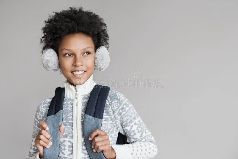 Retrato de una pequeña escuela Gracioso niño afroamericano riéndose usando ropa cálida en estudio, aislado en gris fotografía de archivo libre de regalías