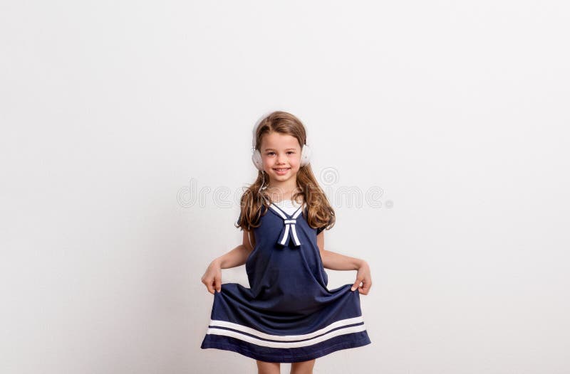 Retrato de una pequeña muchacha con los auriculares en estudio en un fondo blanco fotografía de archivo Retrato de una pequeña muchacha con los auriculares en estudio en un fondo blanco fotografía de archivo