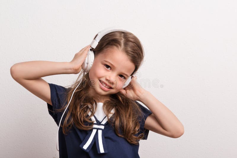 Retrato de una pequeña muchacha con los auriculares en un estudio imagen de archivo libre de regalías Retrato de una pequeña muchacha con los auriculares en un estudio imagen de archivo libre de regalías