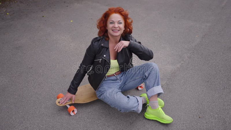 Retrato de vista de gran angular atractiva mujer retro tocando el pelo mirando la cámara sentada en patineta en la carretera. disp almacen de video