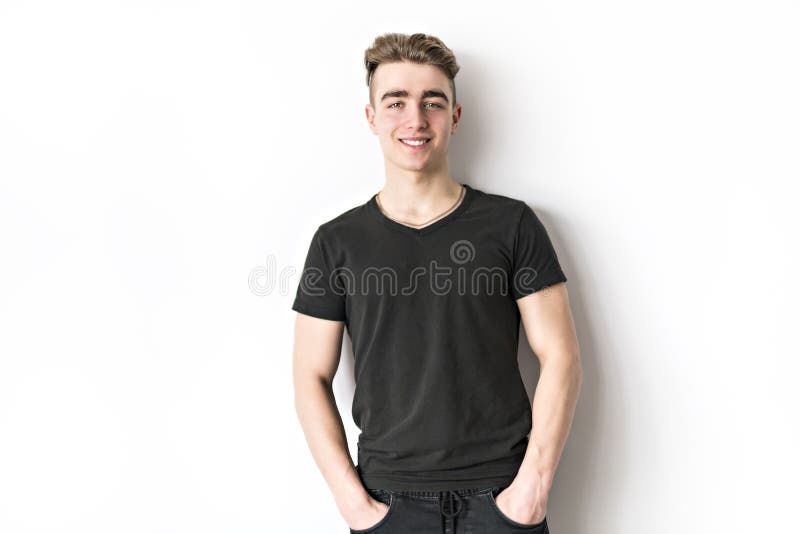 Retrato del adolescente lindo sonriente joven en la pared blanca imagenes de archivo Retrato del adolescente lindo sonriente joven en la pared blanca imagenes de archivo