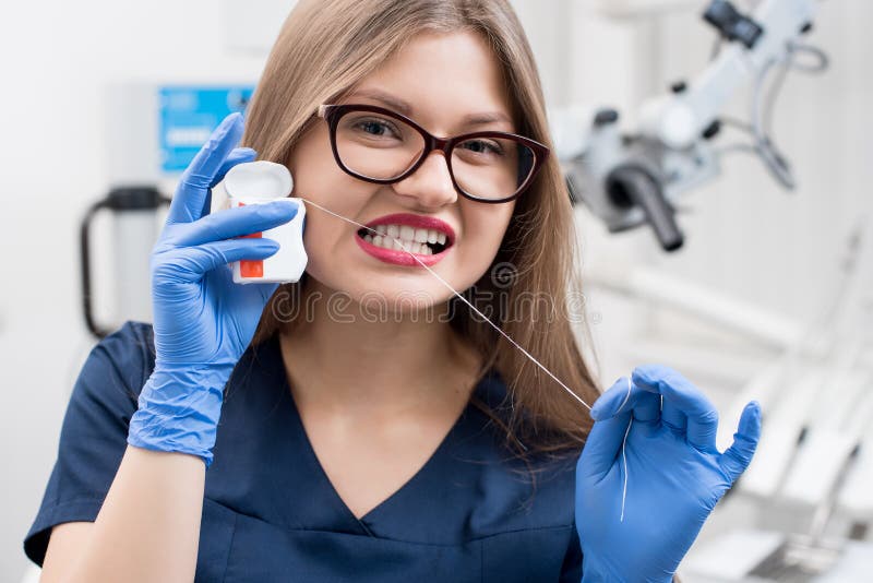 Retrato del dentista de sexo femenino atractivo con seda dental en la clínica dental fotos de archivo Retrato del dentista de sexo femenino atractivo con seda dental en la clínica dental fotos de archivo
