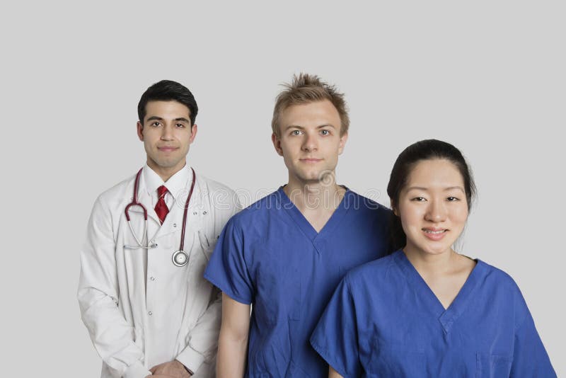 Retrato del equipo médico étnico multi confiado que se coloca sobre fondo gris fotografía de archivo Retrato del equipo médico étnico multi confiado que se coloca sobre fondo gris fotografía de archivo