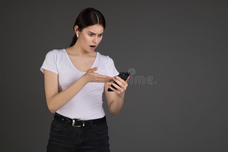 Retrato del estudio de la mujer shoked y confusa que recibe tratar y el mensaje molesto vía boca abierta del smartphone fotografía de archivo Retrato del estudio de la mujer shoked y confusa que recibe tratar y el mensaje molesto vía boca abierta del smartphone fotografía de archivo