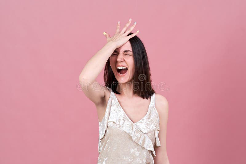 Retrato del estudio de una mujer morena atractiva joven que grita de la tensión y que presiona su palma a su cabeza imágenes de archivo libres de regalías Retrato del estudio de una mujer morena atractiva joven que grita de la tensión y que presiona su palma a su cabeza imágenes de archivo libres de regalías