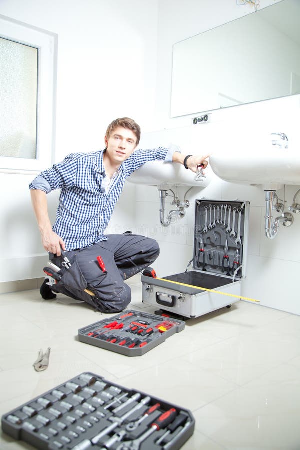 Retrato del fontanero de sexo masculino que fija un fregadero en cuarto de baño imagenes de archivo Retrato del fontanero de sexo masculino que fija un fregadero en cuarto de baño imagenes de archivo