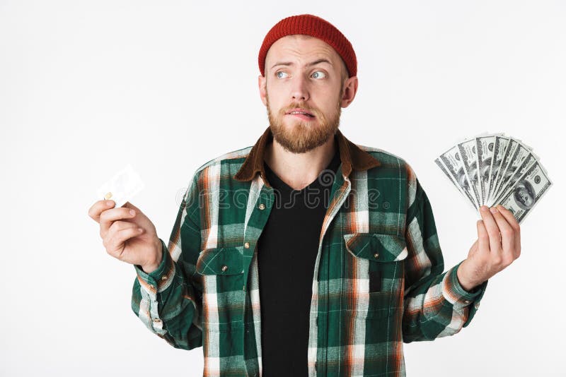Retrato del hombre atractivo que sostiene la tarjeta de crédito y del fan del dinero del dólar, mientras que se coloca aislado so foto de archivo libre de regalías Retrato del hombre atractivo que sostiene la tarjeta de crédito y del fan del dinero del dólar, mientras que se coloca aislado so foto de archivo libre de regalías