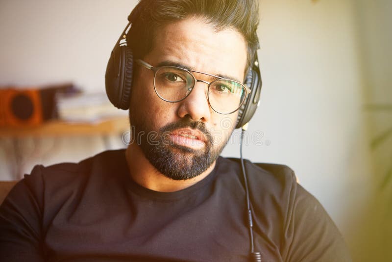 Retrato del hombre barbudo hermoso en auriculares que escucha la música en casa Concepto del tiempo de la relajación y de resto e fotografía de archivo libre de regalías Retrato del hombre barbudo hermoso en auriculares que escucha la música en casa Concepto del tiempo de la relajación y de resto e fotografía de archivo libre de regalías
