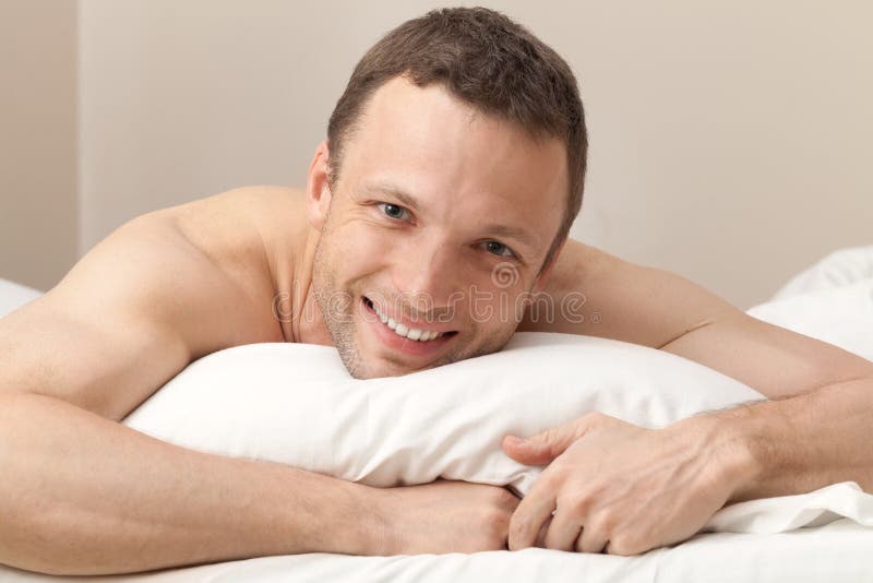 Retrato del hombre joven contento en cama imágenes de archivo libres de regalías Retrato del hombre joven contento en cama imágenes de archivo libres de regalías