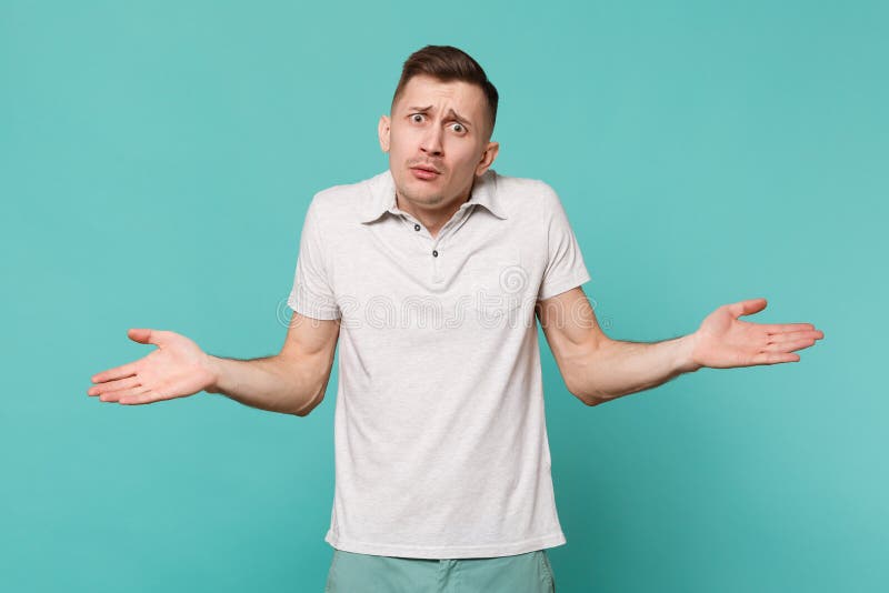 Retrato del hombre joven perplejo en la ropa casual que coloca y que separa las manos aisladas en la pared azul de la turquesa imagenes de archivo Retrato del hombre joven perplejo en la ropa casual que coloca y que separa las manos aisladas en la pared azul de la turquesa imagenes de archivo