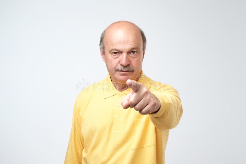 Retrato del hombre mayor serio con el finger amonestador y la camisa amarilla de la camiseta contra fondo gris claro fotografía de archivo libre de regalías Retrato del hombre mayor serio con el finger amonestador y la camisa amarilla de la camiseta contra fondo gris claro fotografía de archivo libre de regalías