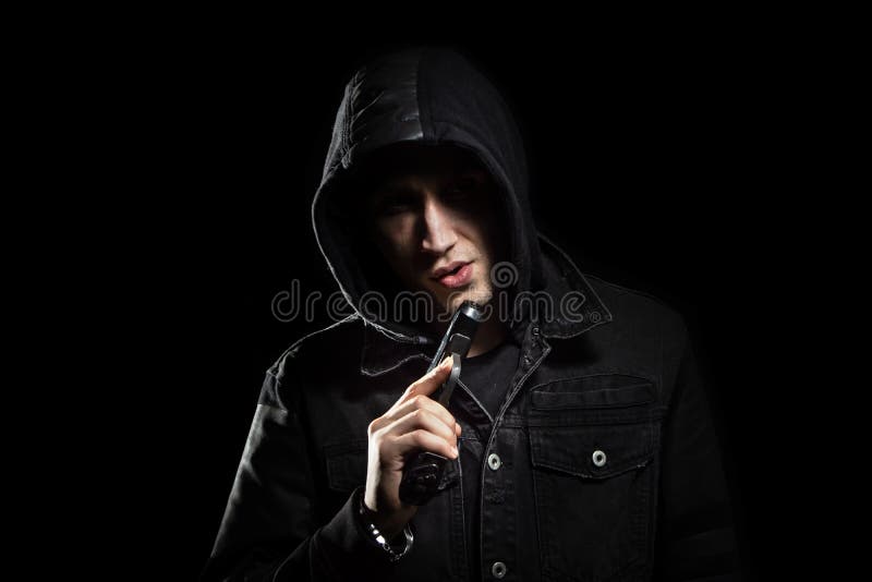 Retrato del hombre serio con el arma en el negro de la capilla foto de archivo libre de regalías Retrato del hombre serio con el arma en el negro de la capilla foto de archivo libre de regalías