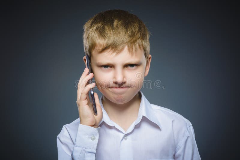 Retrato del muchacho de la ofensa con el móvil o el teléfono celular Emoción humana negativa