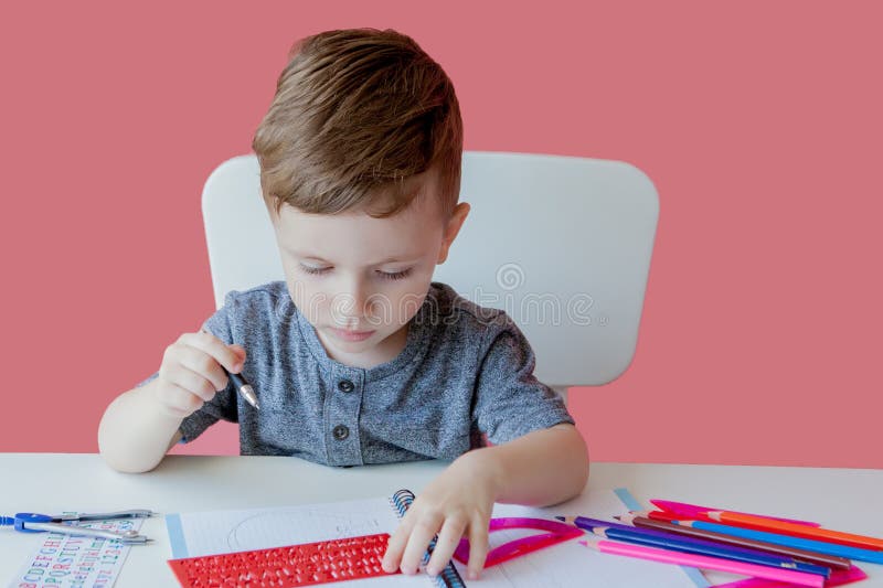 Retrato del muchacho lindo del niño en casa que hace la preparación Poco niño concentrado que escribe con el lápiz colorido, dent fotografía de archivo Retrato del muchacho lindo del niño en casa que hace la preparación Poco niño concentrado que escribe con el lápiz colorido, dent fotografía de archivo