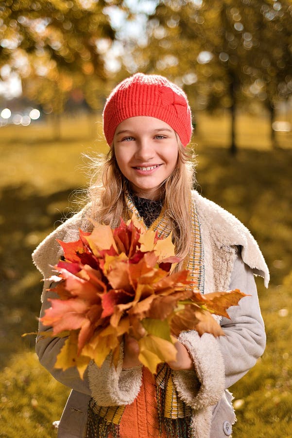 Retrato del otoño de la muchacha linda en sombrero y capa rojos imagen de archivo Retrato del otoño de la muchacha linda en sombrero y capa rojos imagen de archivo