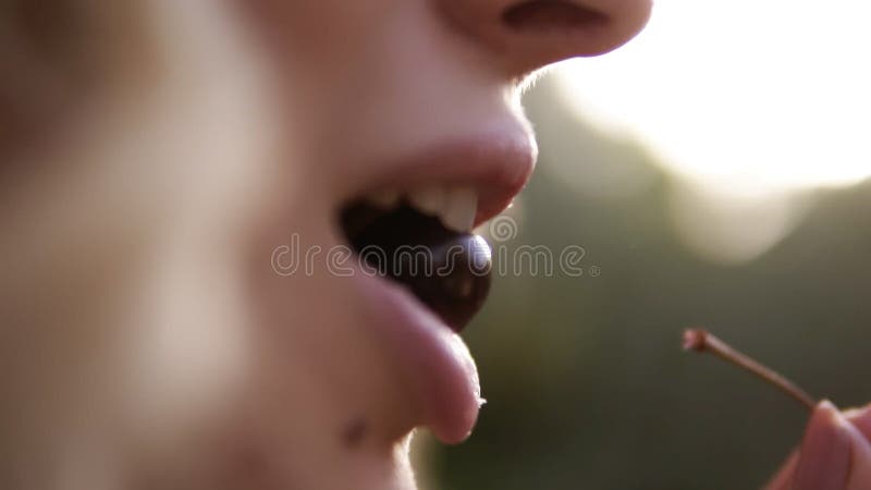 Retrato del primer de la cara hermosa del ` s de la mujer que come una cereza Apunte la cantidad de una boca del ` s de la mujer