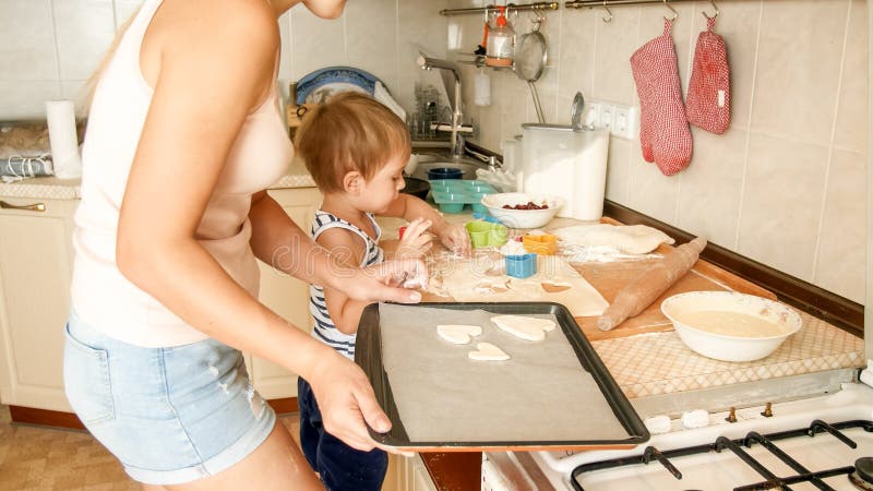 Retrato del primer de la madre joven que enseña a su hijo del niño que hace las galletas Niño con los postres de la hornada del p imagen de archivo Retrato del primer de la madre joven que enseña a su hijo del niño que hace las galletas Niño con los postres de la hornada del p imagen de archivo