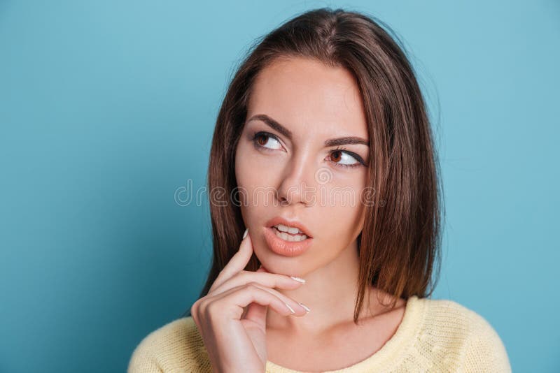 Retrato del primer de la muchacha pensativa que piensa sobre fondo azul fotografía de archivo Retrato del primer de la muchacha pensativa que piensa sobre fondo azul fotografía de archivo