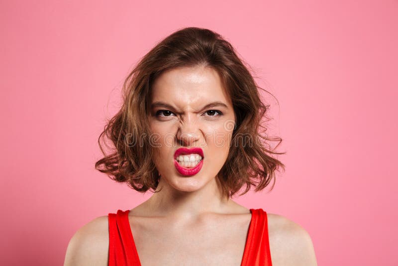 Retrato del primer de la mujer joven enojada con los labios rojos que miran foto de archivo