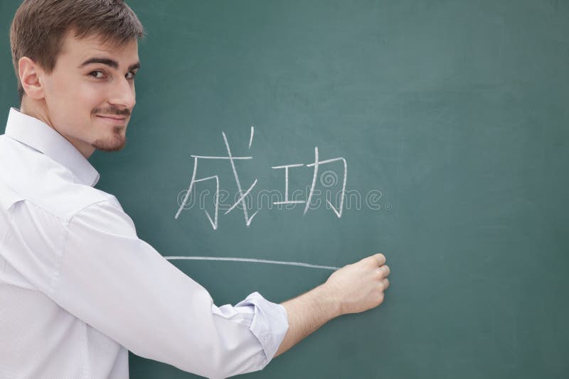 Retrato del profesor de sexo masculino sonriente delante de la escritura de la pizarra, caracteres chinos imagen de archivo libre de regalías Retrato del profesor de sexo masculino sonriente delante de la escritura de la pizarra, caracteres chinos imagen de archivo libre de regalías