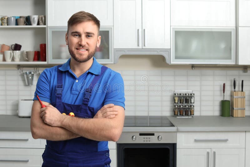 Retrato del reparador con las herramientas cerca del horno en cocina foto de archivo libre de regalías Retrato del reparador con las herramientas cerca del horno en cocina foto de archivo libre de regalías