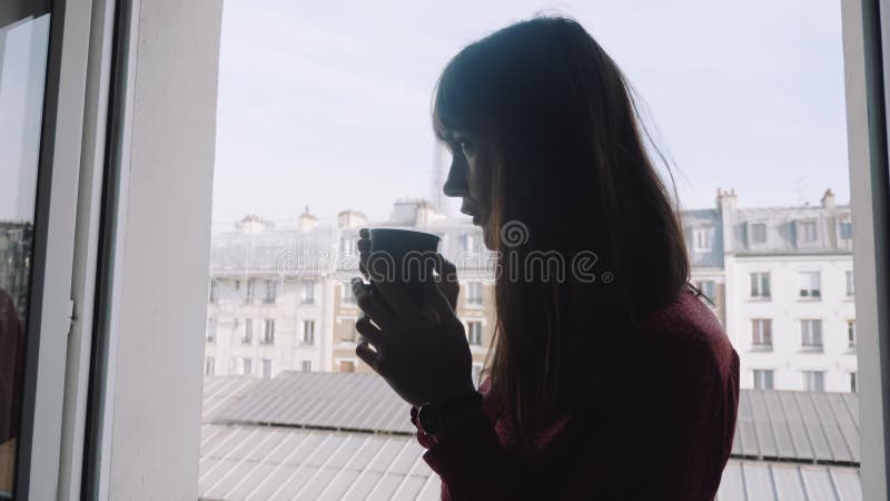 Retrato deslizante de jovem e feliz e relaxada artista que desfruta de café na janela da Torre Eiffel em câmera lenta