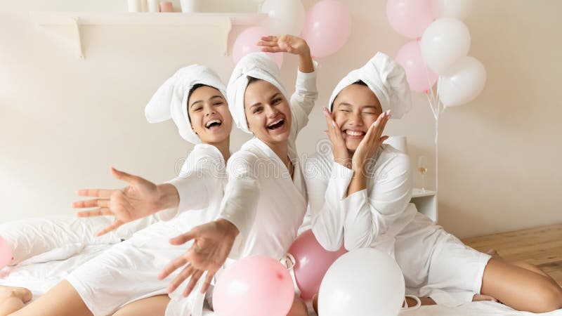 Retrato divertido asiático novia con damas de honor sentado en la cama fotos de archivo