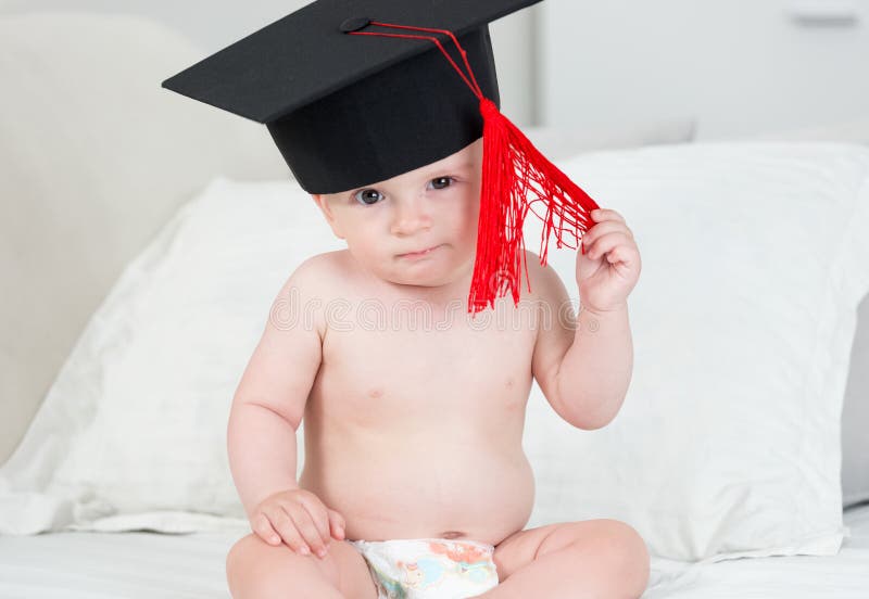 Retrato do bebê adorável no tampão preto da graduação com t vermelho fotos de stock Retrato do bebê adorável no tampão preto da graduação com t vermelho fotos de stock