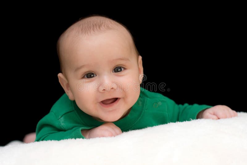 A sweet, precious baby of three months of age is holding his head up for a portrait. Black background. Baby has a big smile. A sweet, precious baby of three months of age is holding his head up for a portrait. Black background. Baby has a big smile.
