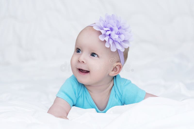 Retrato do bebê pequeno bonito com a flor da curva em sua cabeça foto de stock Retrato do bebê pequeno bonito com a flor da curva em sua cabeça foto de stock