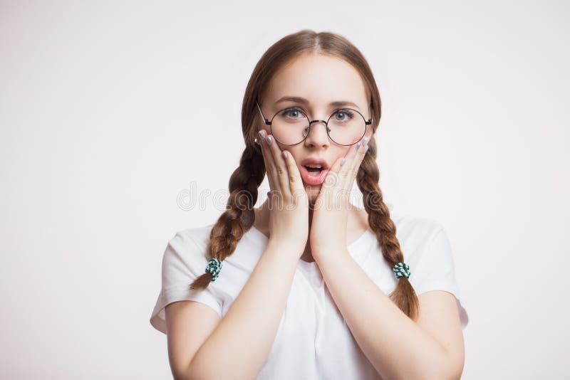 Retrato do close up da menina nova bonita surpreendida do estudante ou do adolescente em vidros e no t-shirt redondos no fundo br fotos de stock royalty free Retrato do close up da menina nova bonita surpreendida do estudante ou do adolescente em vidros e no t-shirt redondos no fundo br fotos de stock royalty free