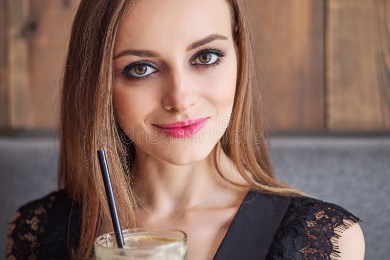 Retrato do close up da mulher adorável nova com composição na moda dos olhos lindos que bebe a xícara de café de vidro grande com imagens de stock Retrato do close up da mulher adorável nova com composição na moda dos olhos lindos que bebe a xícara de café de vidro grande com imagens de stock