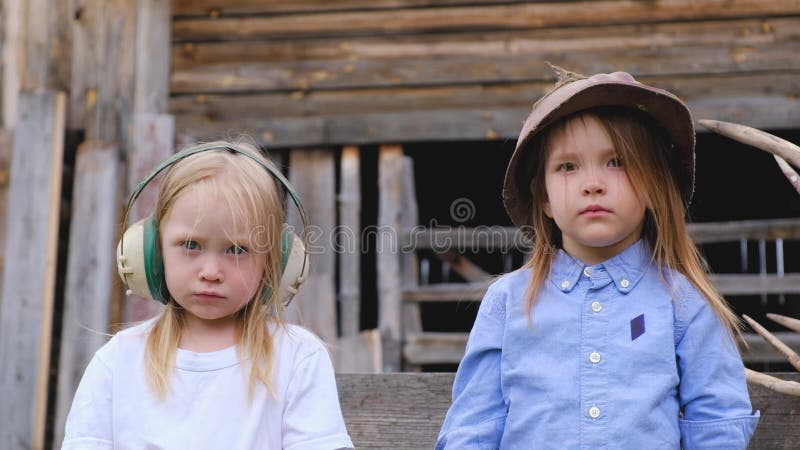 Retrato do close-up de duas crianças bonitas das meninas que levantam no capacete empoeirado
