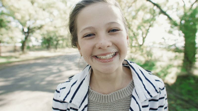 Retrato do close-up de uma menina de sorriso nova Uma menina doce olha a câmera e ri